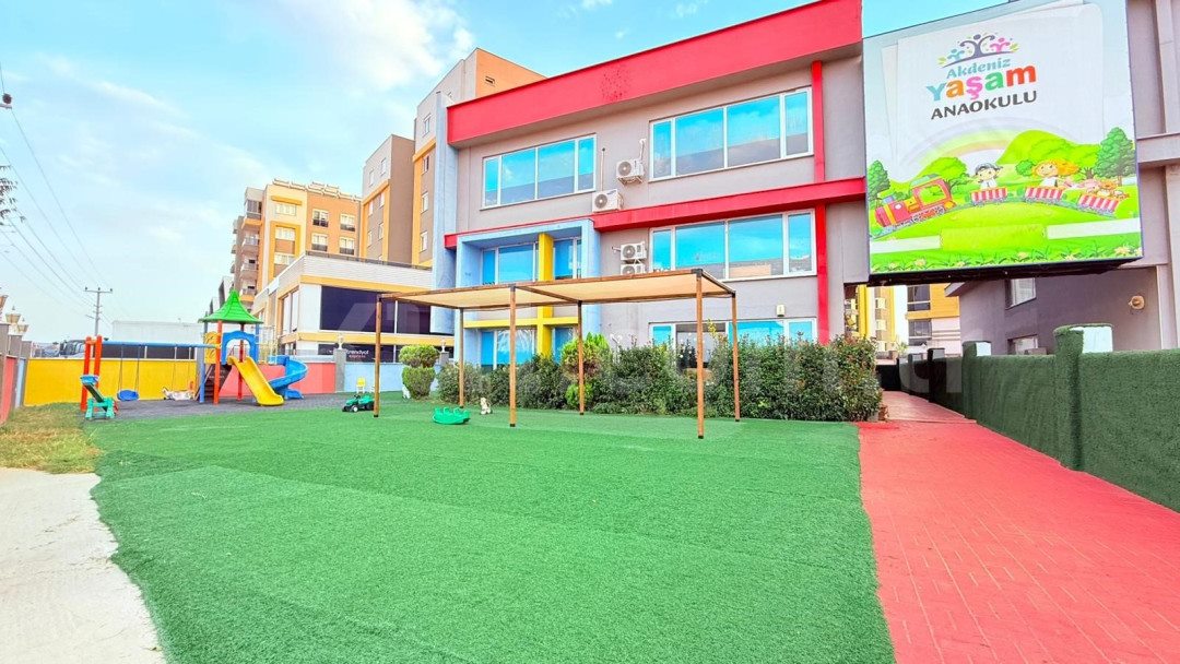 Çim kaplı kapalı oyun bahçesi ve oyun grubu